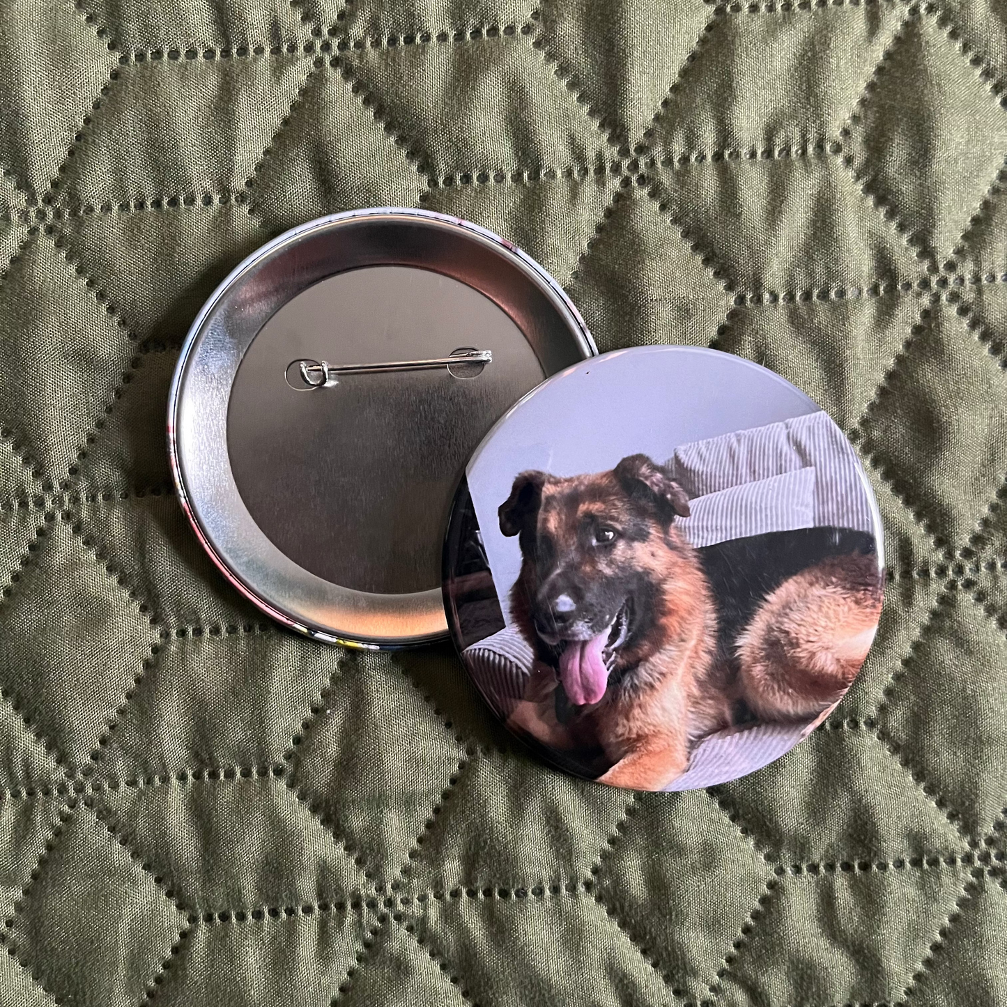 Button badge with a dog design on a green quilted surface