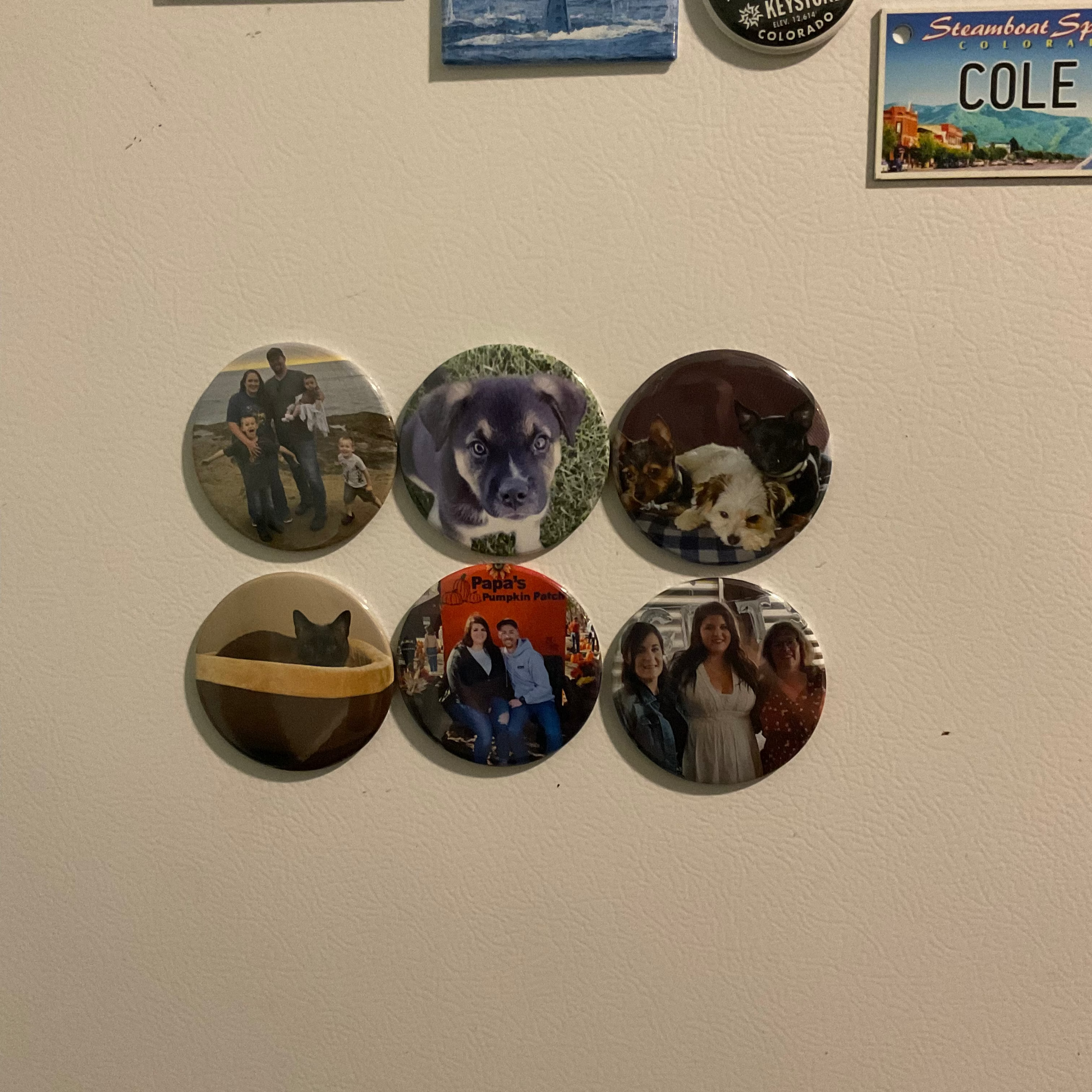 Collection of round magnets on a white refrigerator