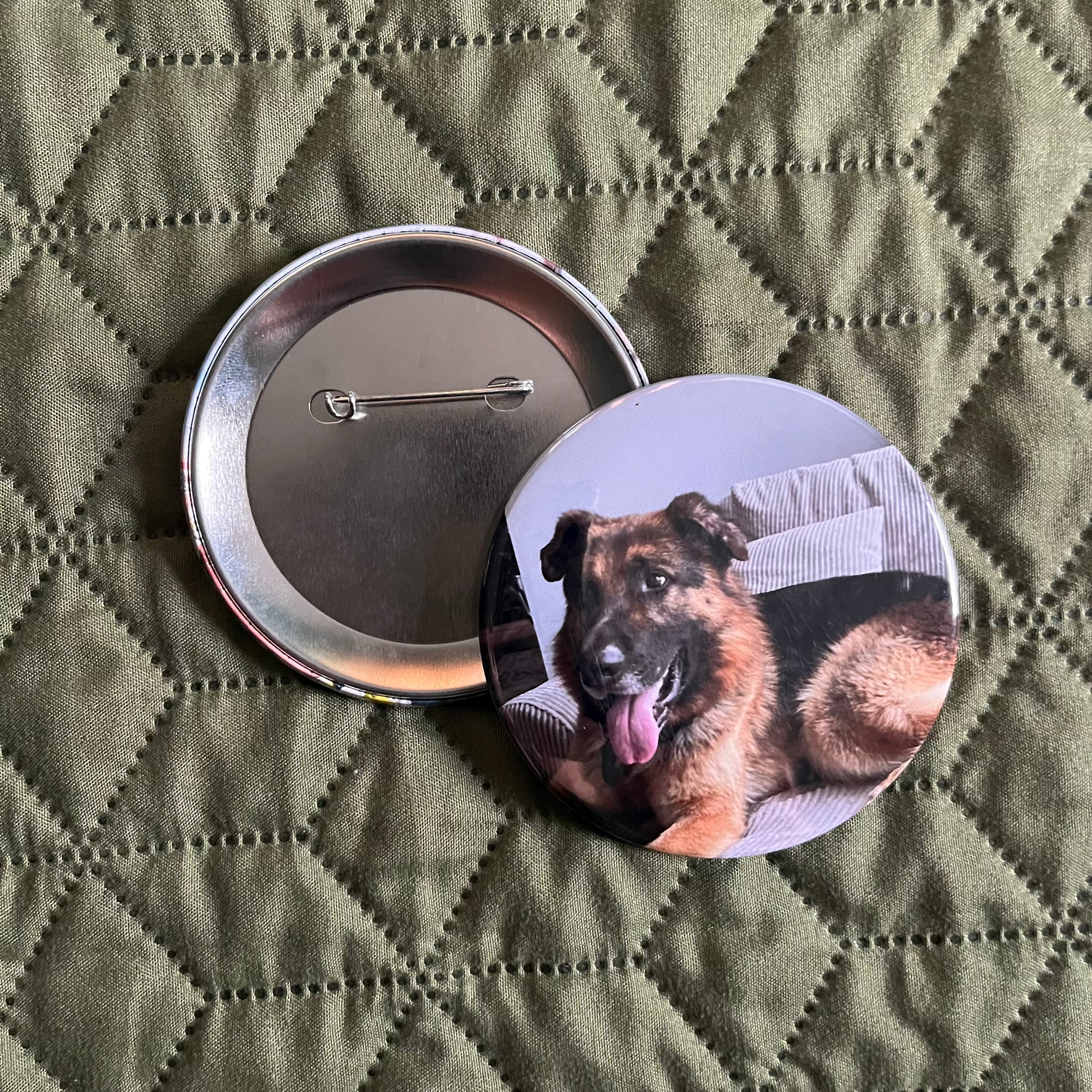 Button badge with a dog design on a green quilted surface
